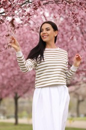 Photo of Pretty young woman in park with blooming trees. Spring look