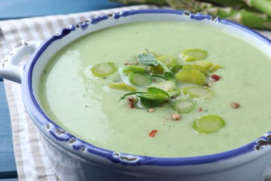 Photo of Delicious asparagus soup in bowl on table, closeup
