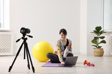 Photo of Happy sports blogger recording fitness lesson with camera at home