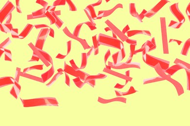 Image of Bright red confetti falling on light yellow background