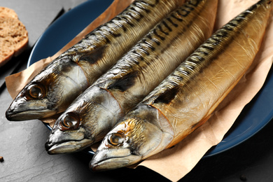 Photo of Tasty smoked fish on black table, closeup