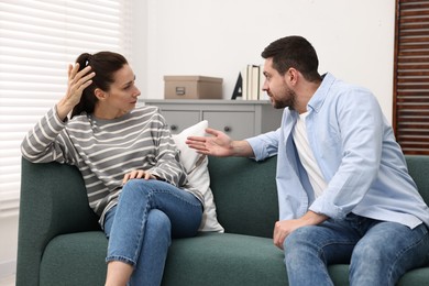 Photo of Emotional couple arguing on sofa indoors. Relationship problems