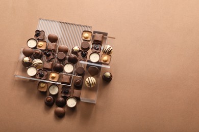 Photo of Heart made with delicious chocolate candies on brown background, top view. Space for text