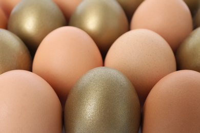 Photo of Golden eggs among others as background, closeup