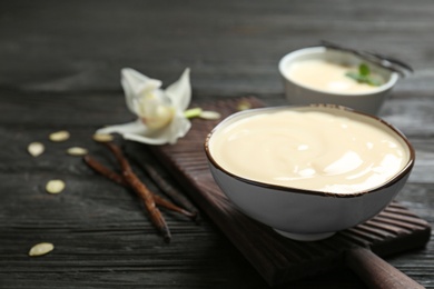 Photo of Vanilla pudding, sticks and flower on wooden background