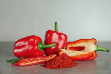 Photo of Fresh chili and bell peppers with paprika powder on grey table