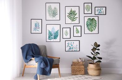 Photo of Beautiful paintings of tropical leaves on white wall in living room interior