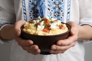Photo of Woman holding bowl of delicious traditional Ukrainian banosh, closeup