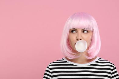 Photo of Beautiful woman blowing bubble gum on pink background, space for text