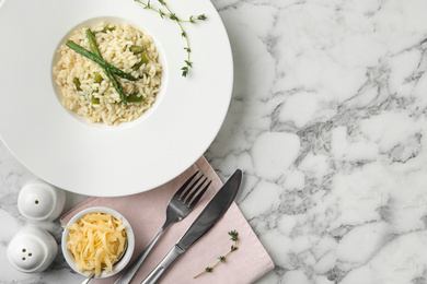 Photo of Delicious risotto with asparagus served on marble table, flat lay