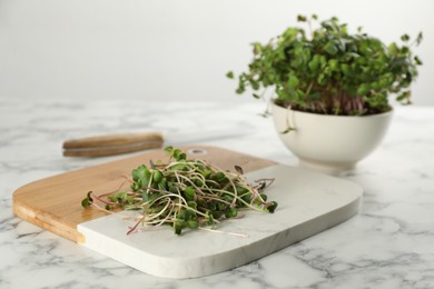 Photo of Board with fresh radish microgreens on white marble table