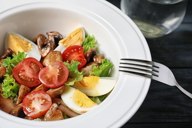 Photo of Plate with delicious fresh salad on table, closeup