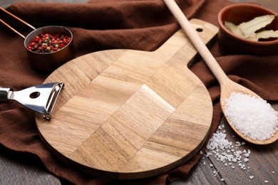 Photo of Cooking utensils with different spices on wooden table, closeup