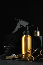 Photo of Different hairdresser tools on grey table against black background