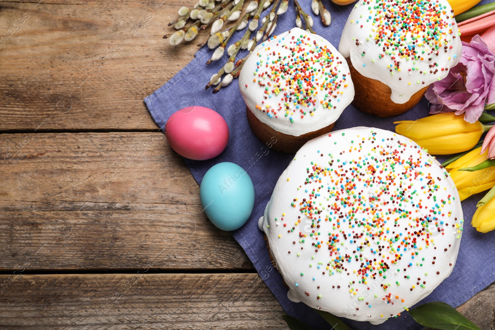 Photo of Flat lay composition with Easter cakes on wooden table. Space for text