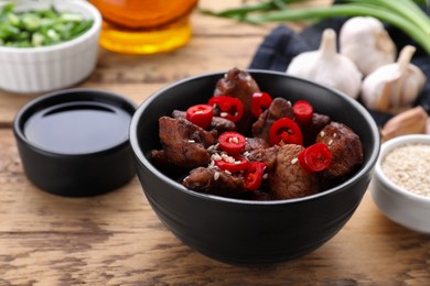 Photo of Tasty roasted meat served with soy sauce on wooden table, closeup