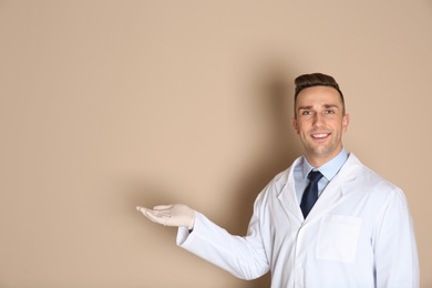 Photo of Male dentist holding something on color background. Space for text