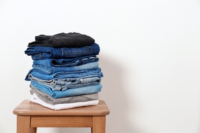Photo of Stack of different jeans on table against white background. Space for text