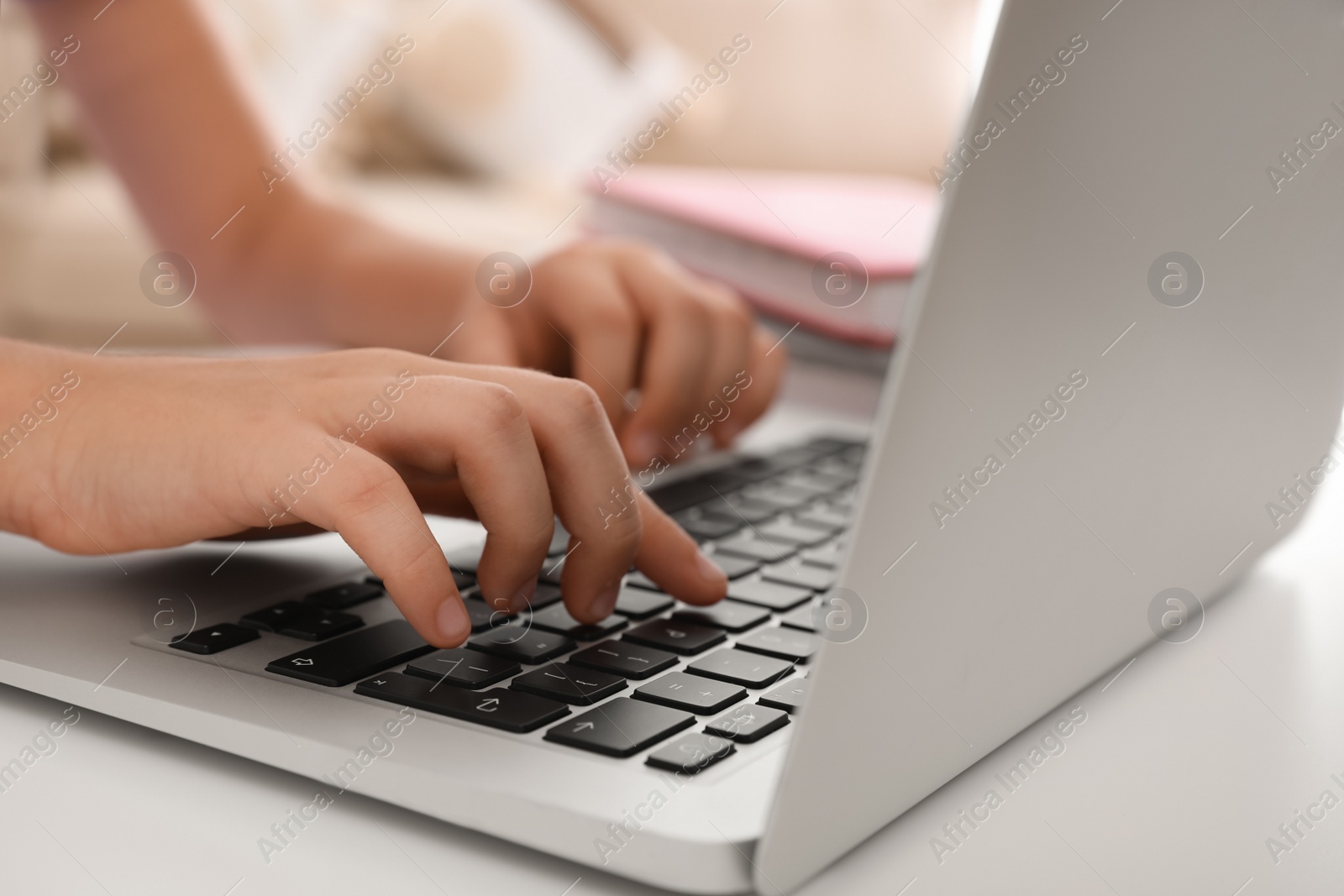 Photo of Preteen girl doing homework with laptop at table, closeup