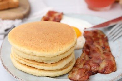 Plate with tasty pancakes and bacon on table, closeup