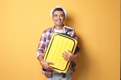 Photo of Young man with suitcase on color background