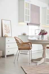 Photo of Dining room interior with tea set on round table and wicker chairs