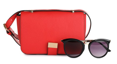 Photo of Red women's leather flap bag and sunglasses on white background