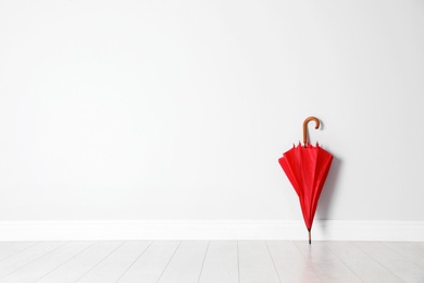 Photo of Beautiful umbrella on floor near white wall with space for design