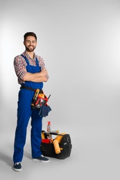 Photo of Full length portrait of construction worker with tools on light background. Space for text