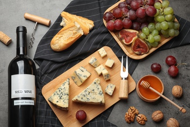 Photo of FLat lay composition with board of delicious blue cheese and wine on stone background