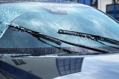 Photo of Washing car windscreen with wipers and liquid, closeup