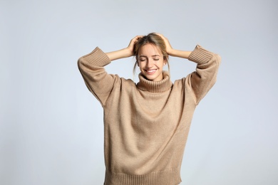 Photo of Beautiful young woman wearing knitted sweater on light grey background