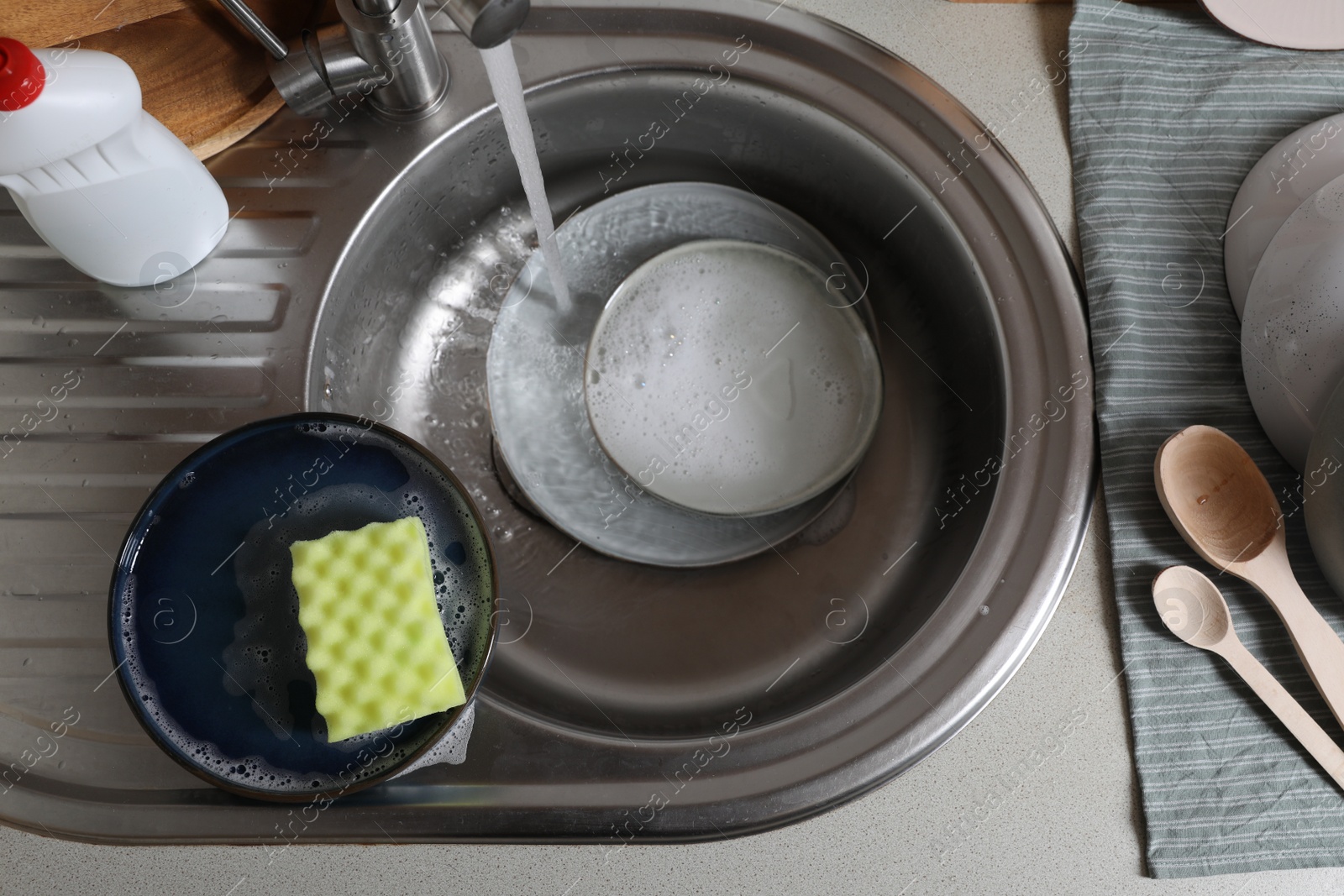 Photo of Washing plates in kitchen sink, above view