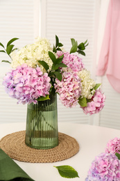 Photo of Bouquet of beautiful hydrangea flowers on white table indoors. Interior design