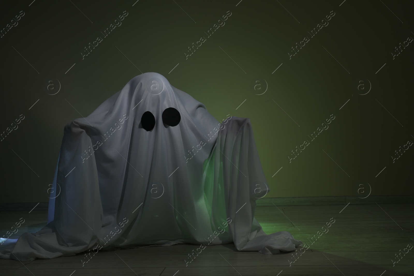 Photo of Creepy ghost. Woman covered with sheet on dark background, space for text