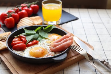 Photo of Delicious fried eggs with spinach, tomatoes and ham served on table