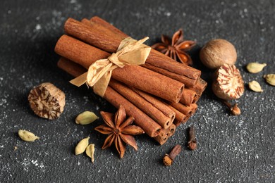 Photo of Different aromatic spices on grey textured table, closeup