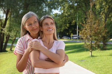 Photo of Family portrait of mother and daughter in park, space for text