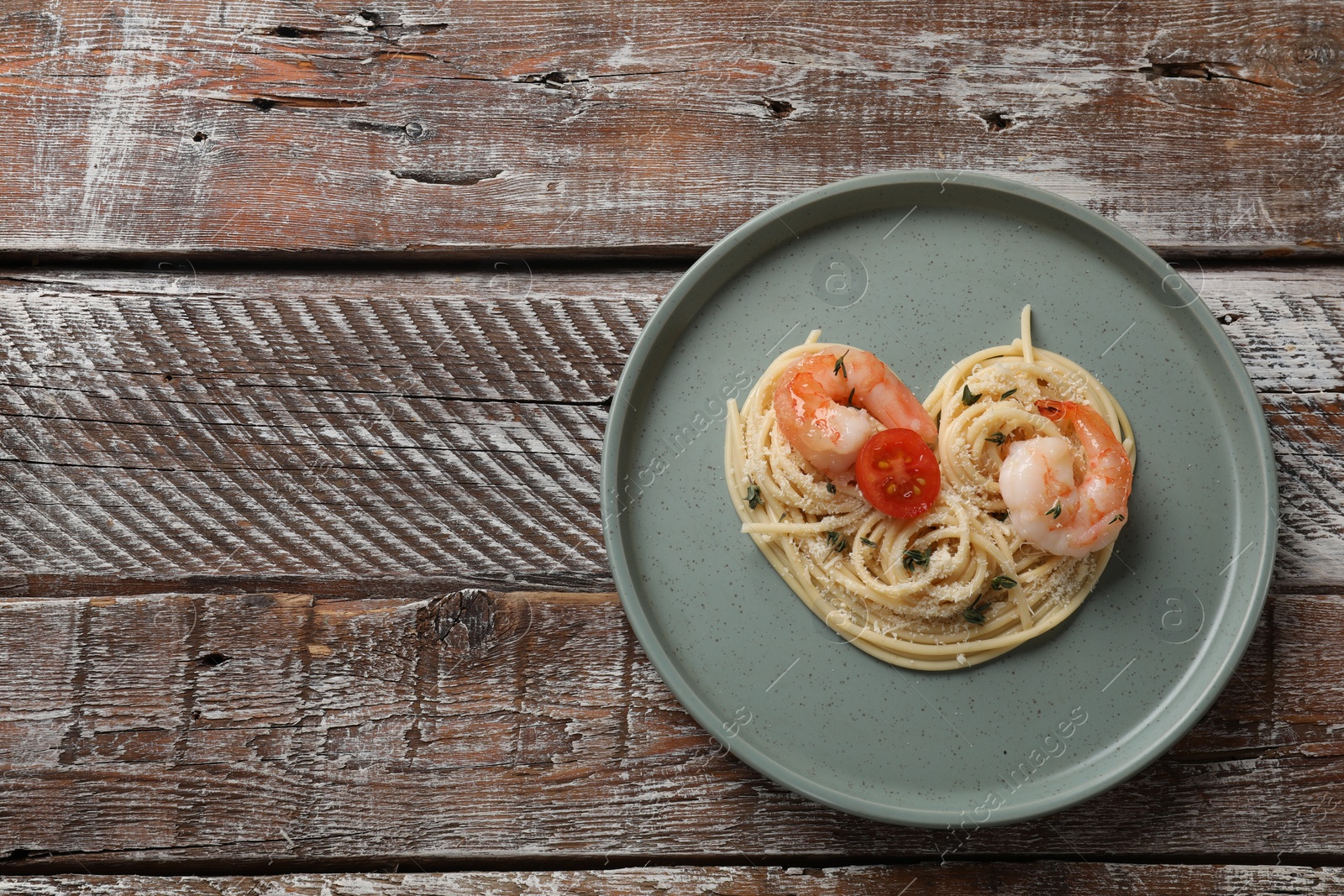 Photo of Heart made of tasty spaghetti, tomato, shrimps and cheese on wooden table, top view. Space for text