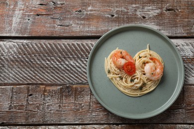 Photo of Heart made of tasty spaghetti, tomato, shrimps and cheese on wooden table, top view. Space for text