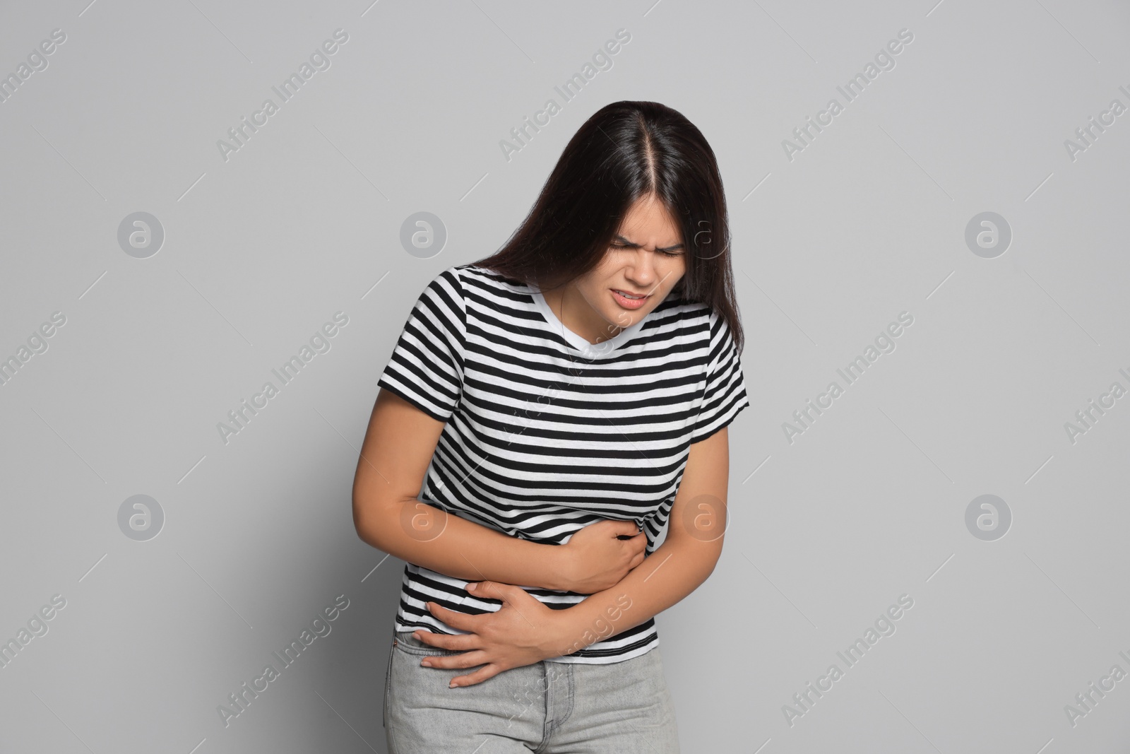 Photo of Young woman suffering from menstrual pain on grey background