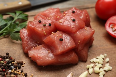 Photo of Cooking delicious goulash. Raw beef meat with different spices on wooden table, closeup