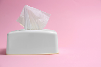 Photo of Holder with paper tissues on pink background
