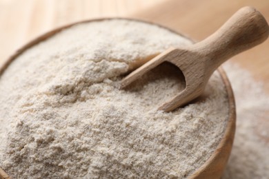 Photo of Quinoa flour in wooden bowl and scoop, closeup