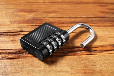 Photo of One steel combination padlock on wooden table, closeup