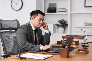 Photo of Notary working with laptop at wooden table in office