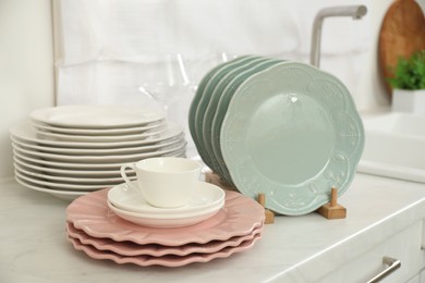 Photo of Clean plates and cup on white marble countertop in kitchen