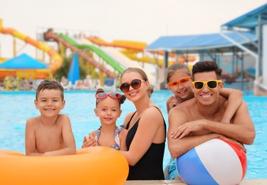 Photo of Happy family with inflatable toys in swimming pool at water park