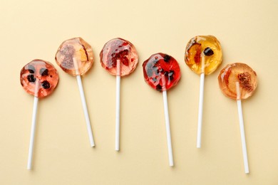 Photo of Sweet colorful lollipops with berries on beige background, flat lay