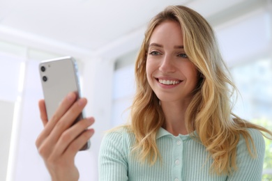 Photo of Young woman unlocking smartphone with facial scanner indoors. Biometric verification